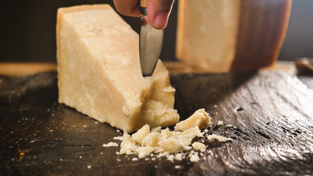 parmesan cheese and cheese knife on wooden board 