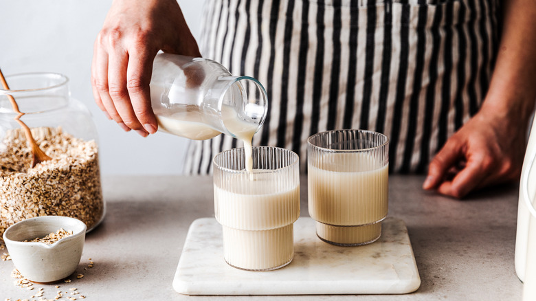 person pouring fresh oat milk