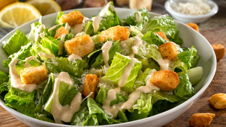 bowl of Caesar salad with parmesan and lemon slices