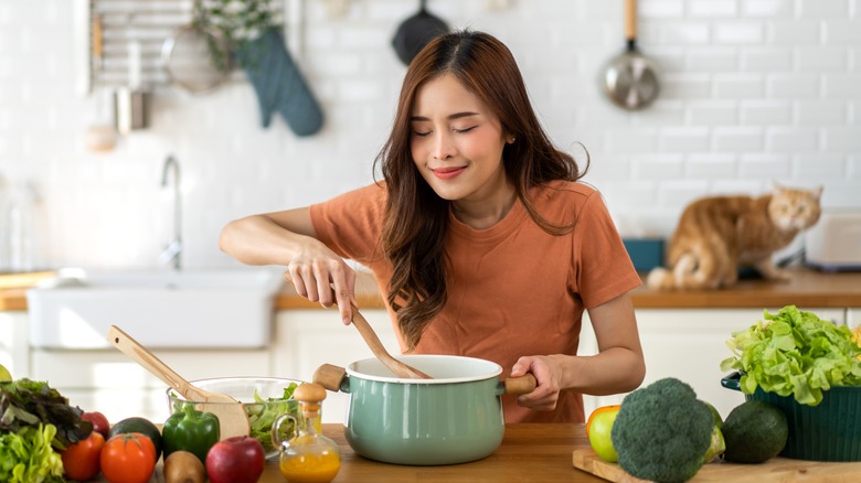 woman smelling food in pot