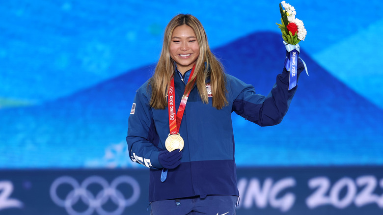 Chloe Kim wearing her gold medal and holding up flowers