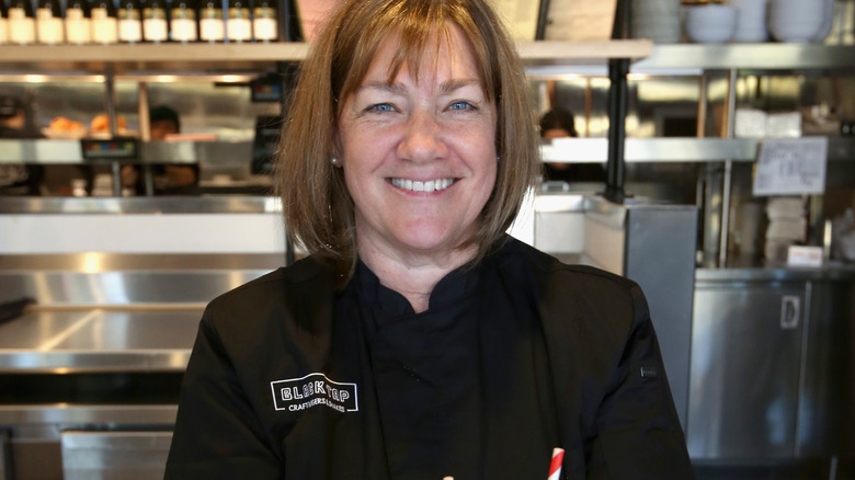 Gale Gand in black coat in kitchen 