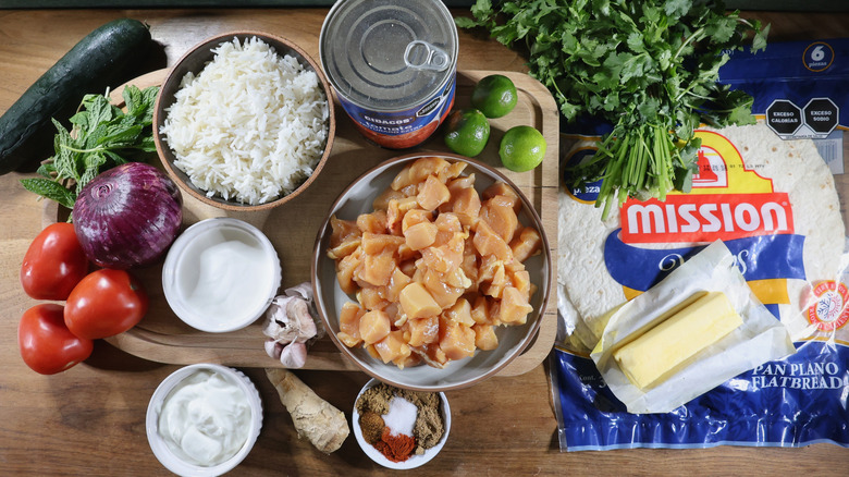 butter chicken burrito ingredients laid out on a wooden table