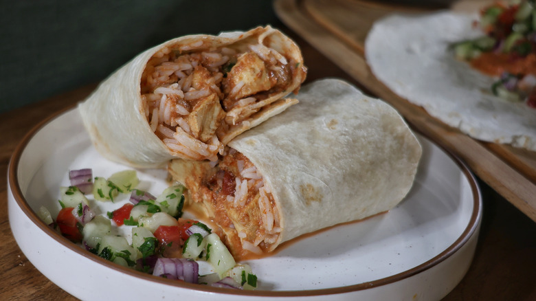 sliced butter chicken burrito on plate with kachumber