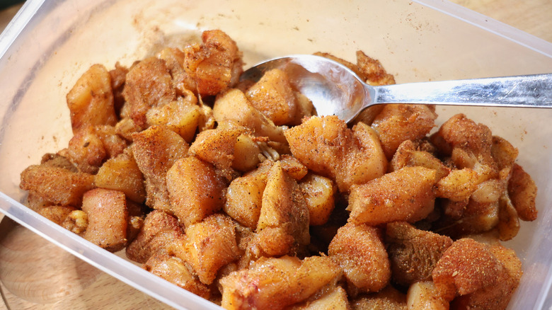 plastic container of chicken pieces coated in spices