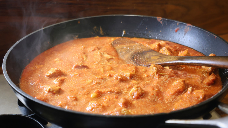 steaming skillet of tomato-based curry