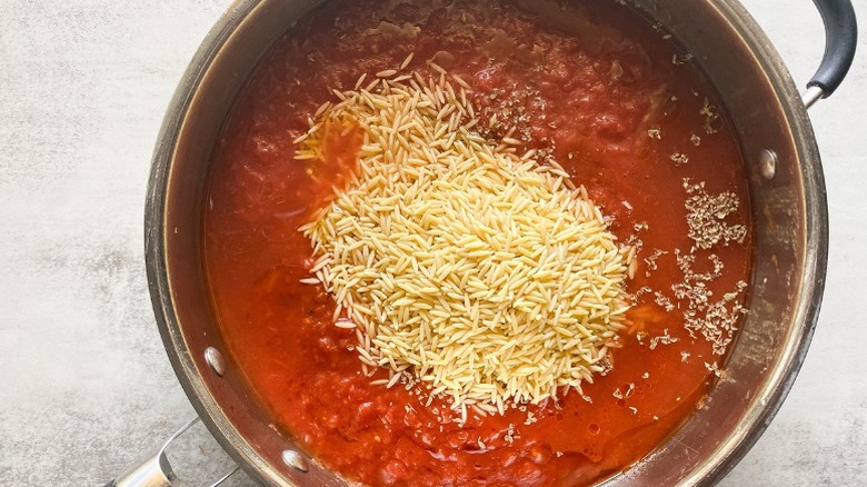 Pot with crushed tomatoes, orzo, and oregano