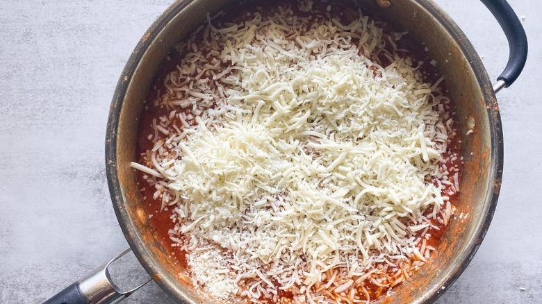 Pot with tomato and orzo topped with shredded mozzarella