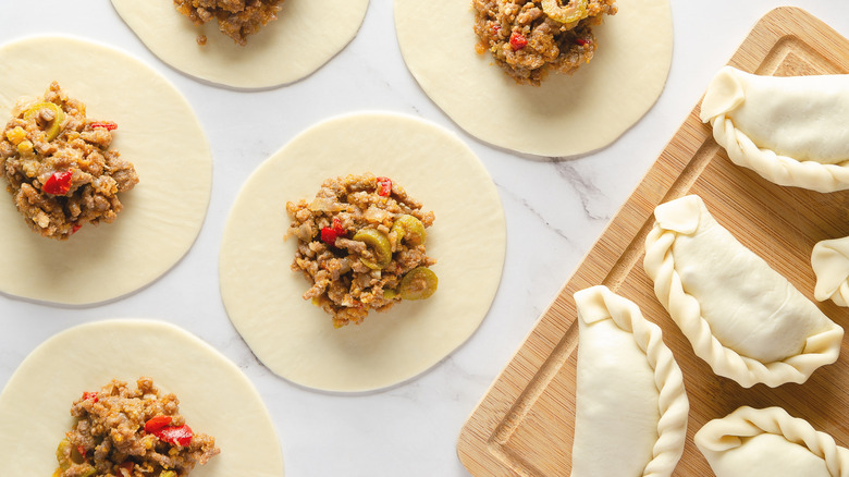 rounds of empanada dough with scoops of beef and onion filling