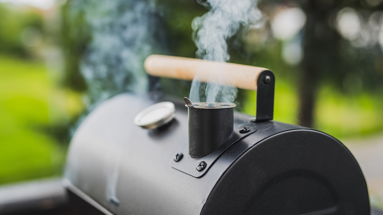 Meat smoker with smoke escaping