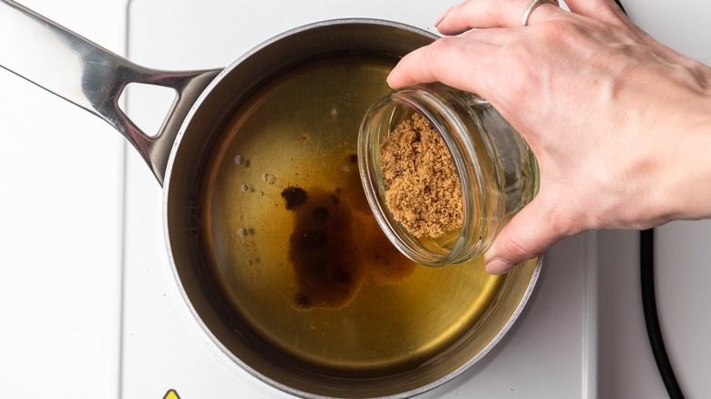 hand adding spices to pan