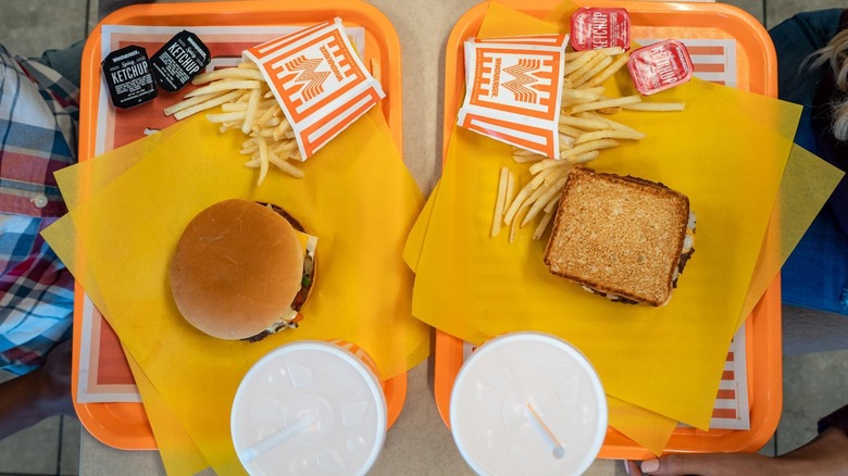 two trays of Whataburger sandwiches and fries with drinks
