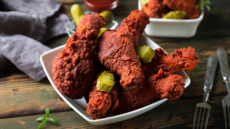 Nashville hot chicken wings in a bowl with pickles