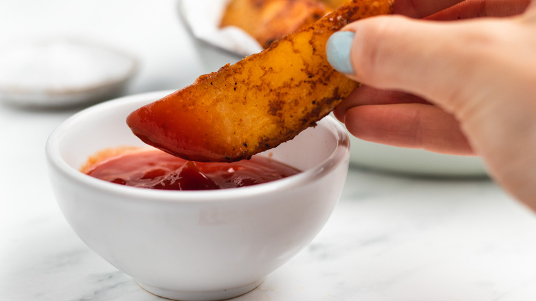 potato wedge dipped in ketchup