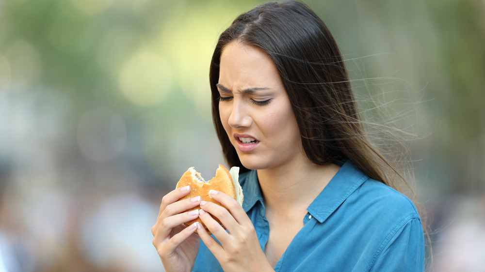 Woman eating bad-tasting sandwich