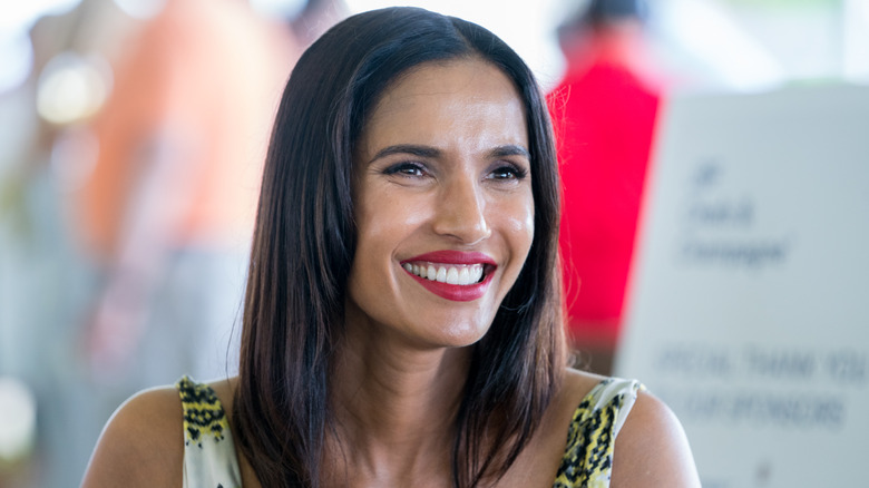 Padma Lakshmi smiles in red lipstick and printed top