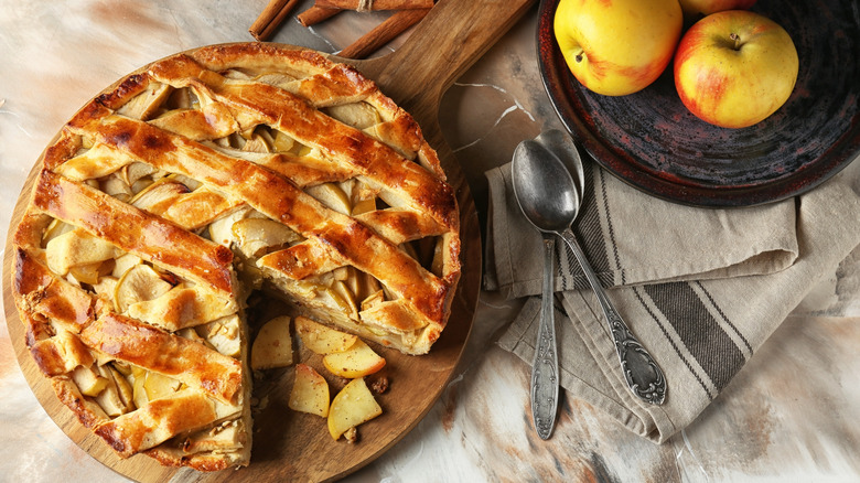 Fresh baked apple pie on table next to spoons