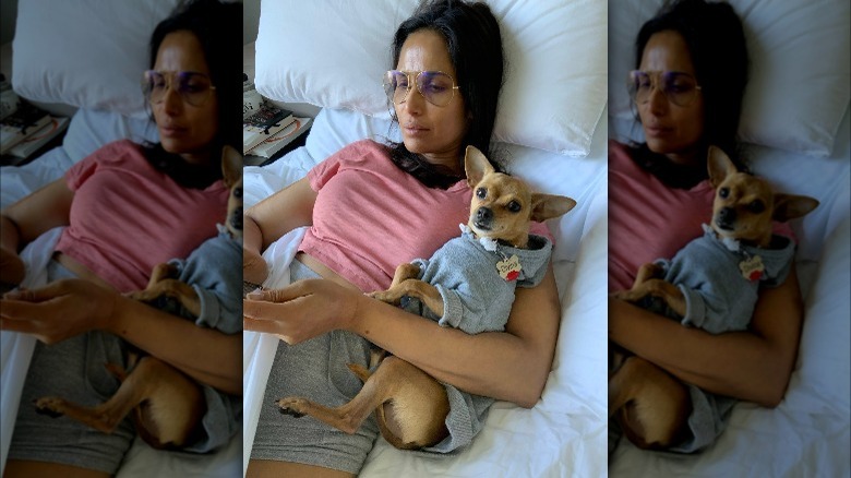 Padma Lakshmi laying with her dog Divina in bed