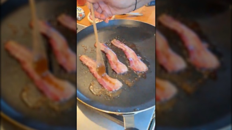 Padma Lakshmi adding honey mustard to bacon in a frying pan