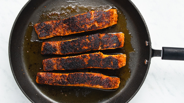 Pan-seared blackened salmon in a frying pan