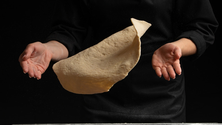 Pizza tossing with hands and black background