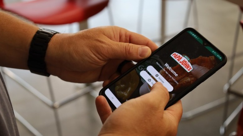 Person holding phone with Papa John's app on screen