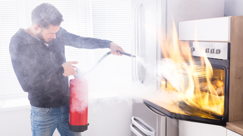 Man putting out oven fire with extinguisher