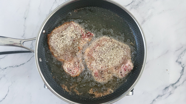 pork cutlets frying in pan