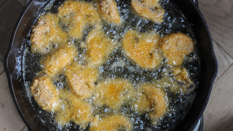 Breaded mushrooms in pan of oil