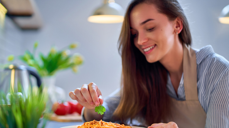 Woman adds parsley to pasta