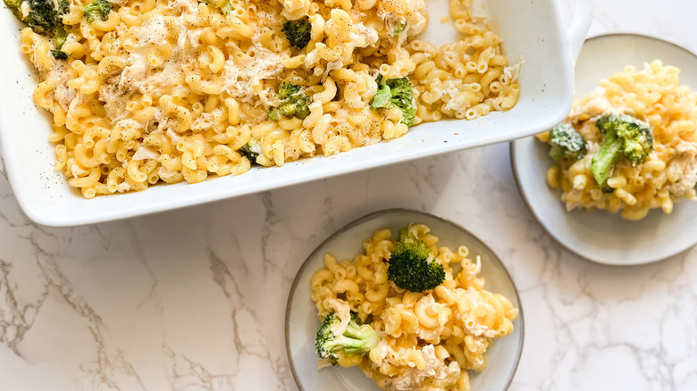 baking dish full of chicken broccoli mac and cheese served onto two plates