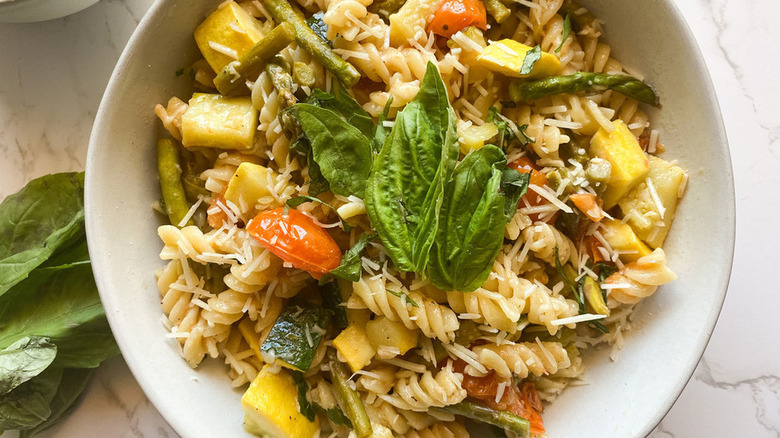 white bowl brimming with pasta primavera topped with bay leaves