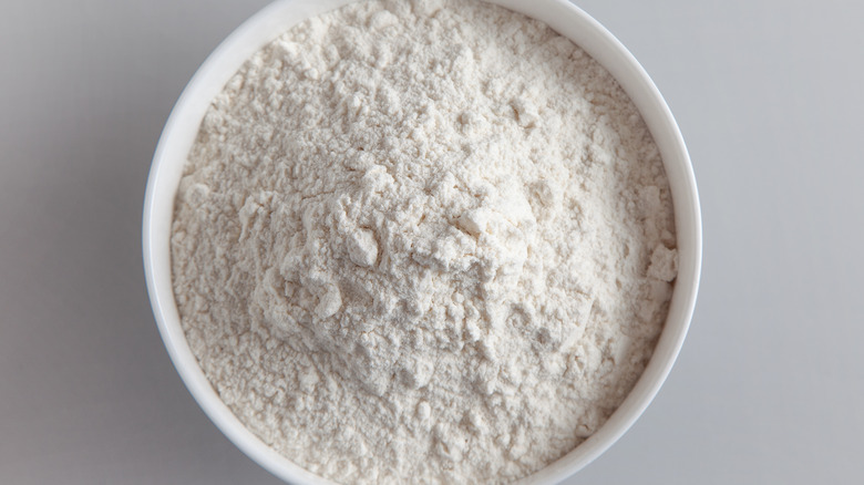 Flour in a white bowl on  gray background