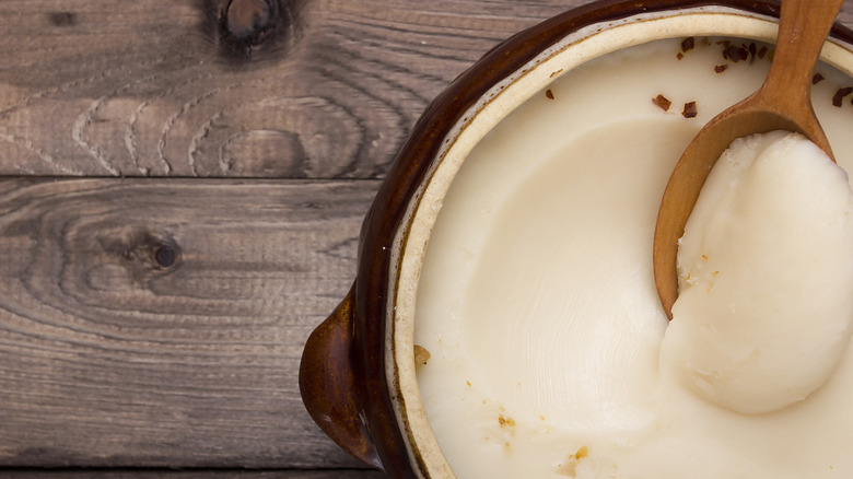 Solidified bacon fat in a ceramic bowl with a wooden spoon