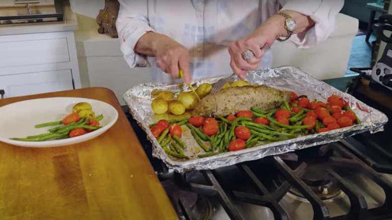 Paula Deen cutting into roast pork tenderloin with green beens and tomatoes