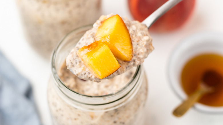 spooning peach overnight oats from jar