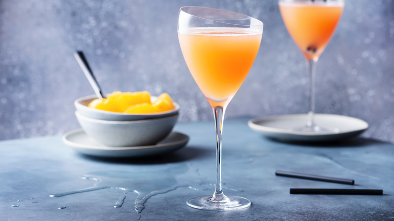 Peach Bellini cocktail with bowl of peaches