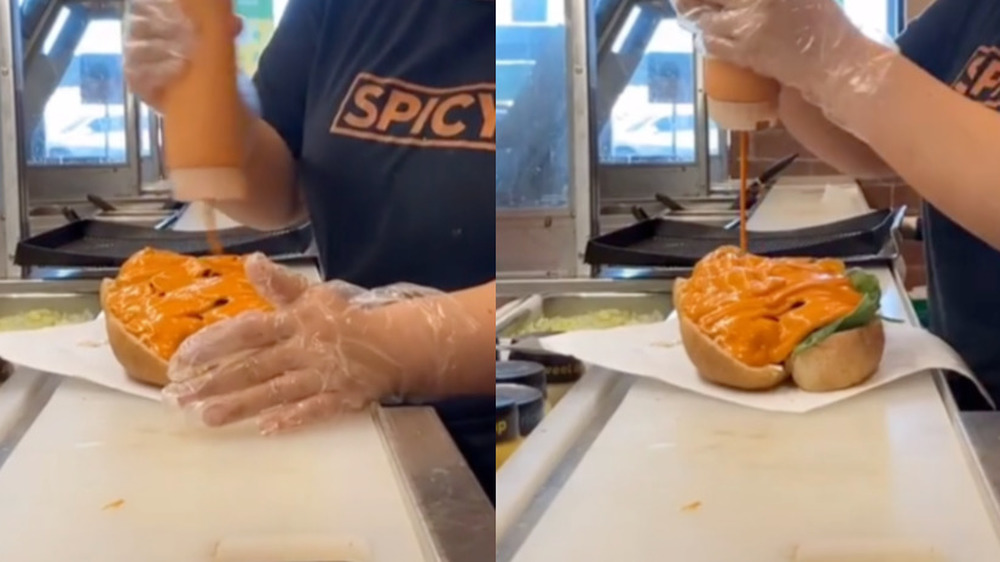 A Subway employee adding sauce