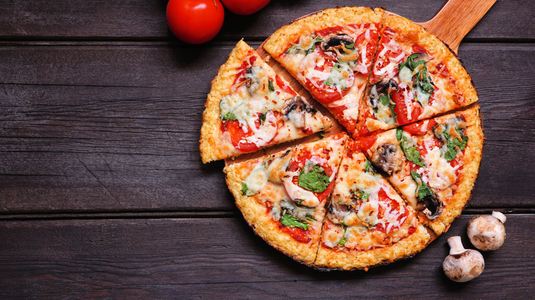 Pizza on dark wood table next to mushrooms