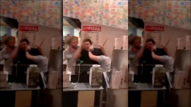 Two kitchen staff members fighting a customer