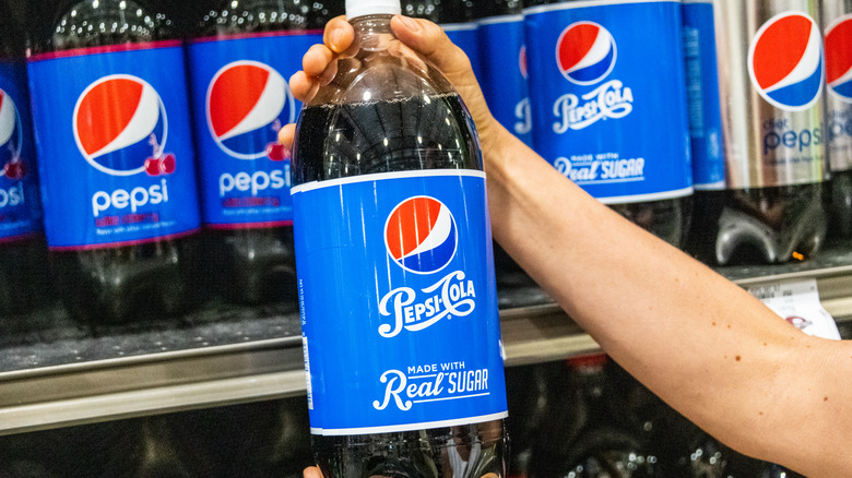 Hands holding two-liter bottle of Pepsi Made With Real Sugar