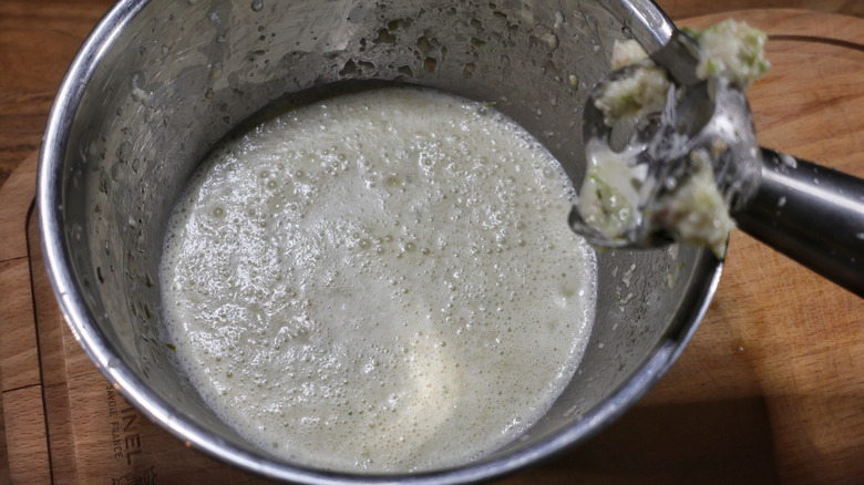 mixing bowl full of leche de tigre with immersion blender resting on it