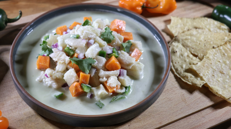 plate of Peruvian-style ceviche in leche de tigre with corn chips and chiles around it