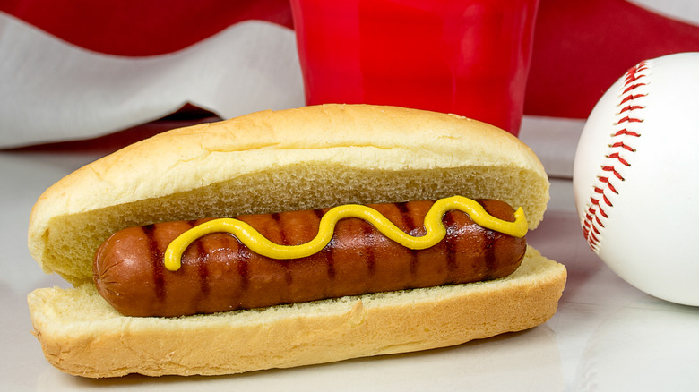 Hot dog with mustard and baseball