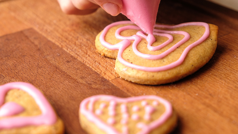 Decorating heart cookie with pink icing