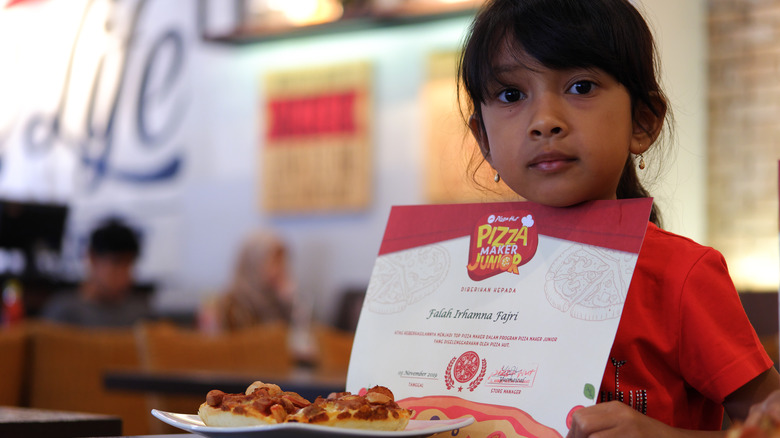 Girl eating Pizza Hut with certificate