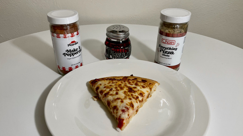 Seasonings, shaker, and pizza slice on plate