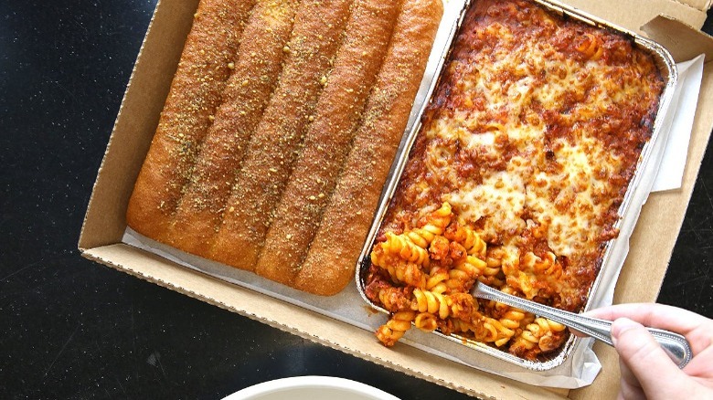 A box containing a tray of Pizza Hut pasta and breadsticks.