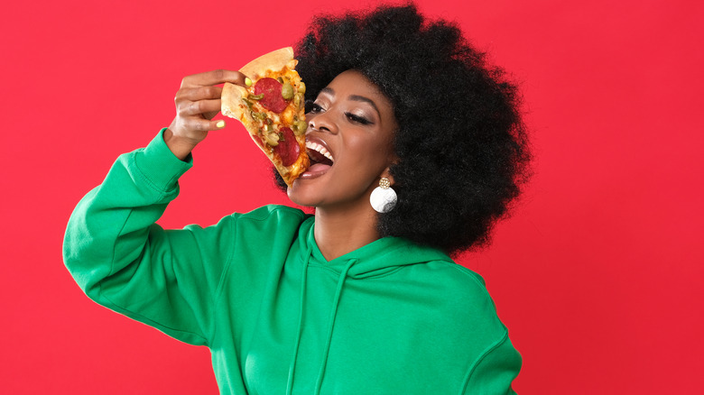 Woman eating pizza in green hoodie