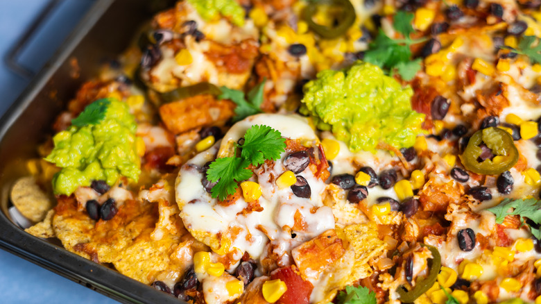 vegan cheese nachos with jackfruit, beans, and corn on baking tray